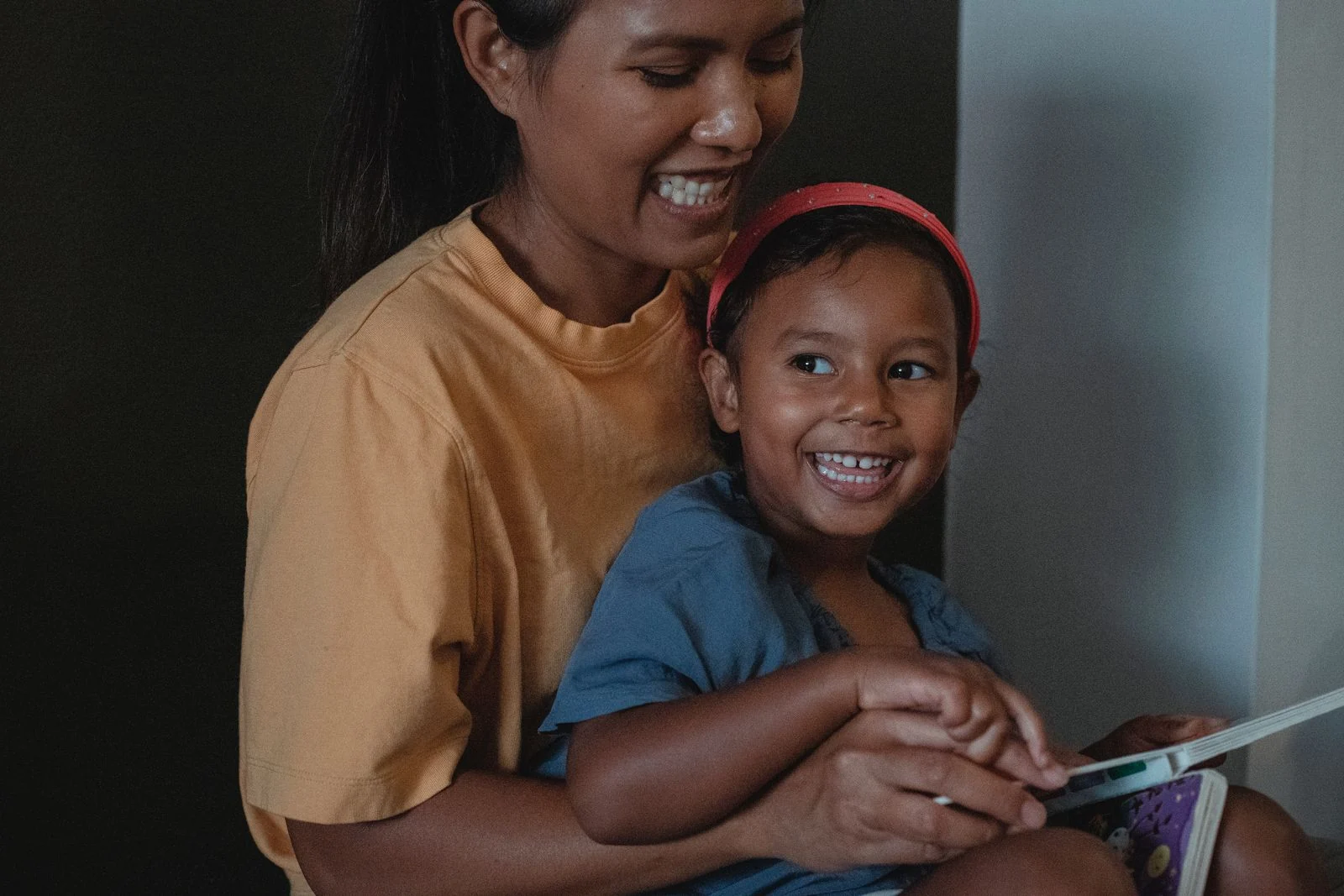 A mother reading a picture book with her smiling child