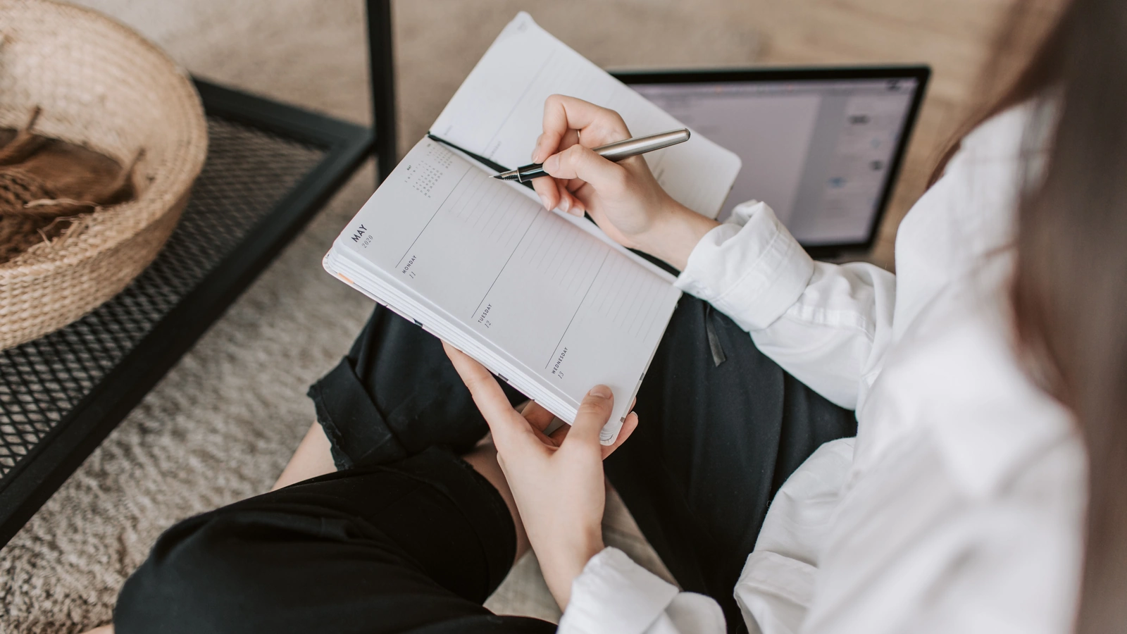 Woman sitting on the floor at home and writing in a notebook.